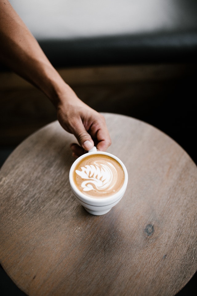 secangkir kopi dengan latte art diatas meja kayu